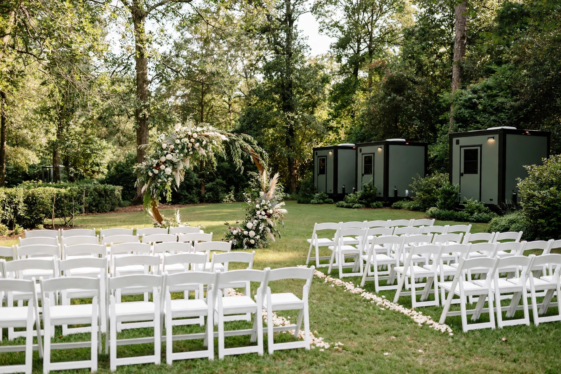 Outdoor wedding ceremony setup with portable restroom units placed discreetly nearby